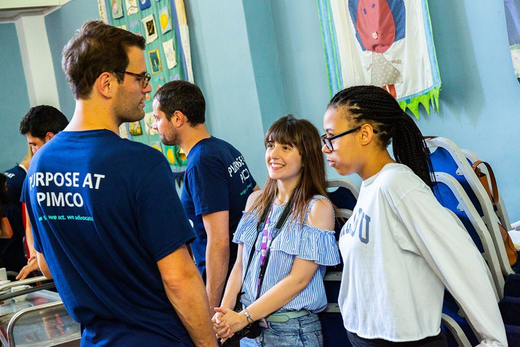 A volunteer chatting to two young women at a community event.