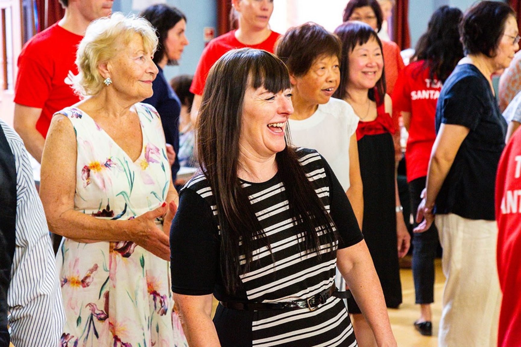 A community event, people are standing watching something, they are smiling and laughing.