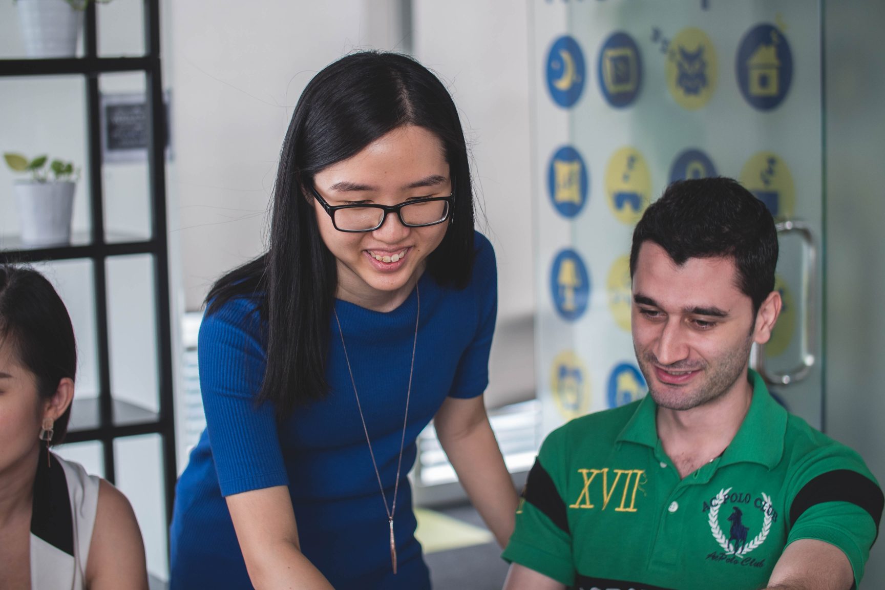 A woman helping a man at a computer.