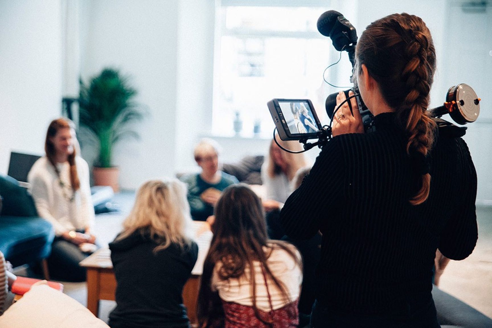 Someone filming a group of people in a room. They are seated comfortably.